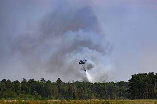 Robert Michael/dpa | Ein Löschhubschrauber ist beim Waldbrand in der Gohrischheide im Einsatz.