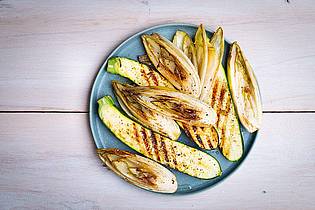 Ariane Bille/BVEO/dpa-tmn | Die länglich geschnittenen Zucchini- und Chicorée-Streifen werden mit einer Marinade aus Olivenöl, Limettensaft, Salz und Pfeffer eingepinselt, dann auf jeder Seite 2?3 Minuten gegrillt.