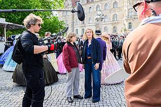 Julian Stratenschulte/dpa | Die Schauspielerinnen Luise von Stein (l) und Maria Furtwängler stehen bei Dreharbeiten für einen neuen «Tatort» inmitten des realen Schützenausmarsches am Neuen Rathaus.