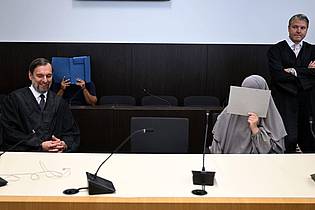 Federico Gambarini/dpa | Der Angeklagte und die Mitangeklagte verdecken ihre Gesichter. (Archivbild)