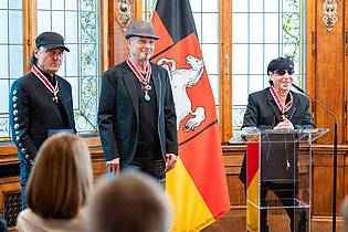 Michael Matthey/dpa | Vor zwei Jahren erhielten Matthias Jabs, Rudolf Schenker und Klaus Meine das Große Verdienstkreuz des Niedersächsischen Verdienstordens. (Archivbild)