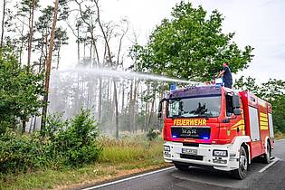 Robert Michael/dpa | In einigen Gebieten können die Einsatzkräfte wegen Munitionsresten im Boden nur vom Fahrzeug aus löschen. 