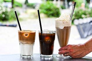 Jens Kalaene/dpa | Iced Latte, Iced Coffee (also Kaffee mit Eiswürfeln) und klassischer Eiskaffee mit Vanilleeis und Sahne - präsentiert in einem Berliner Café.