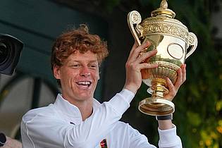 Joanna Chan/AP/dpa | Jannik Sinner präsentiert die Trophäe für den Wimbledonsieg.