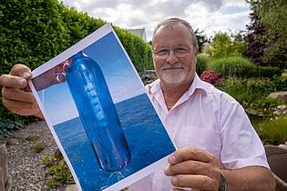 Stefan Sauer/dpa | Jörg Wanke zeigt ein Foto seiner Flaschenpost.