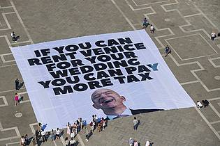 Greenpeace/Greenpeace/AP/dpa | Mit einem Plakat auf dem Markusplatz fordern Greenpeace-Aktivisten, Bezos höher zu besteuern.