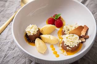 Christin Klose/dpa-tmn | Dessert-Teller mit Schokoladen- und Mango-Mousse auf Mangopüree. Getoppt wird alles mit Eiswaffelsplittern, Schokoraspeln, Himbeeren und Minzblättern. 