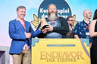 Annette Riedl/dpa | Als «Kennerspiel des Jahres» wurde «Endeavor: Die Tiefsee» von Carl de Visser (2.v.l.) und Jarrat Gray (l) ausgezeichnet.
