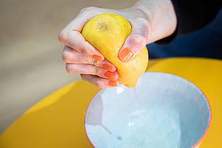 Christin Klose/dpa-tmn | Schritt 2: Zitrone mit der Hand auspressen - der Saft spritzt kontrolliert in die Schale.