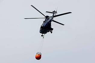 Daniel Wagner/dpa | Ein Löschhubschrauber der Bundespolizei fliegt über dem Zeithainer Tagebau und nimmt Wasser auf, um den Waldbrand Gohrischheide zu bekämpfen.